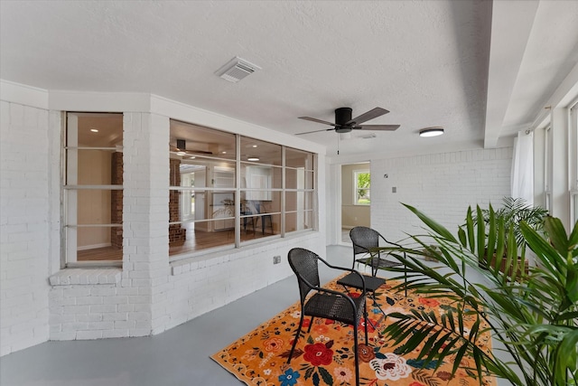 9863 Swan Ct, Conroe, TX 77385 - sunroom with finished concrete flooring, brick wall, ceiling fan, and a textured ceiling