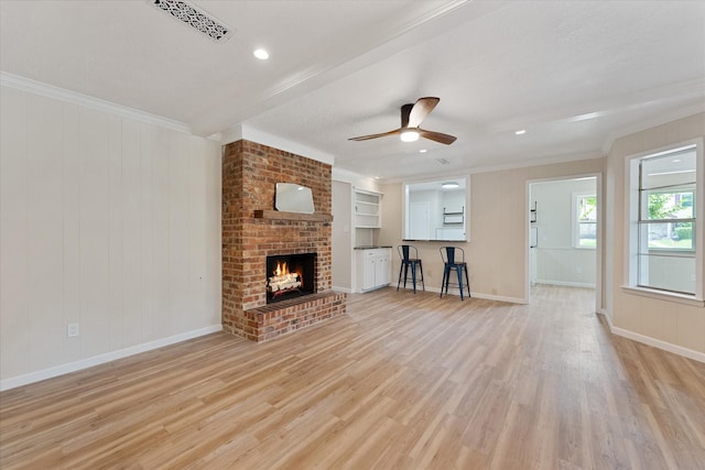 9863 Swan Ct, Conroe, TX 77385 - unfurnished living room with light wood finished floors, ceiling fan, ornamental molding, baseboards, and a brick fireplace