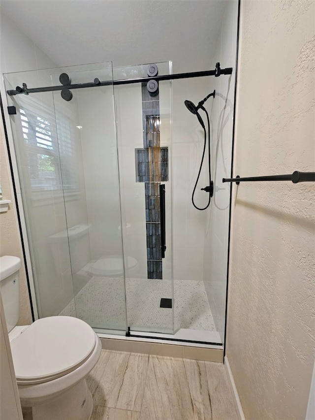 9863 Swan Ct, Conroe, TX 77385 - bathroom featuring toilet, a textured wall, and a stall shower