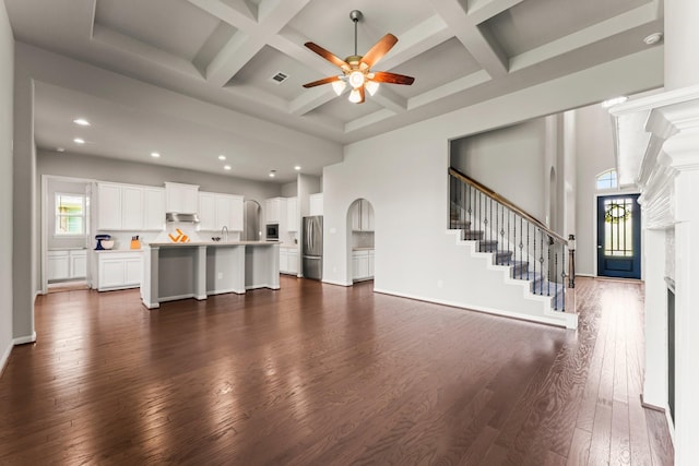 32039 Autumn Orchard Ln, Conroe, TX 77385 - unfurnished living room featuring a ceiling fan, dark wood-style floors, a high ceiling, coffered ceiling, and arched walkways