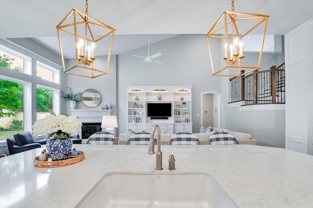 107 E Sawyer Ridge Dr, Spring, TX 77389 - kitchen featuring a chandelier, a sink, ceiling fan, arched walkways, and a glass covered fireplace