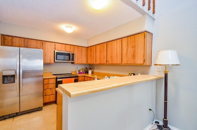 6211 Ludington Dr Unit 21-909, Houston, TX 77035 - kitchen with appliances with stainless steel finishes, light countertops, a peninsula, a textured ceiling, and brown cabinetry