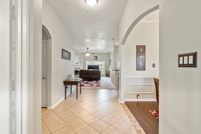 411 Ceole Ln, League City, TX 77573 - corridor featuring arched walkways, light tile patterned floors, a textured ceiling, and baseboards