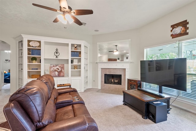 411 Ceole Ln, League City, TX 77573 - living room featuring a ceiling fan, carpet flooring, a tiled fireplace, and arched walkways