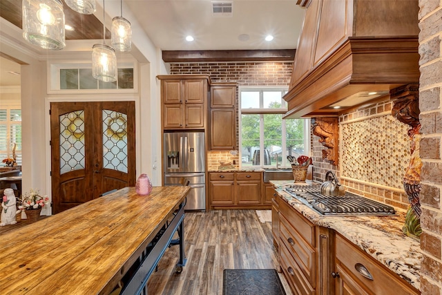 12431 Lake Vista Dr, Willis, TX 77318 - kitchen with stainless steel appliances, dark wood-type flooring, decorative backsplash, light stone counters, and custom exhaust hood