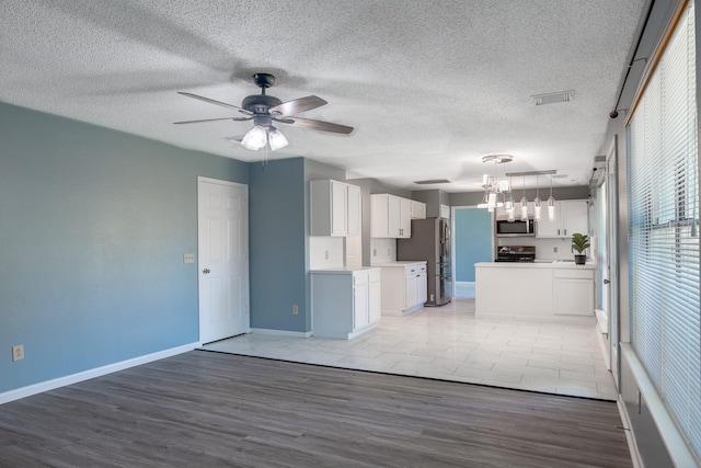 10030 Storm Meadow Dr, Houston, TX 77064 - unfurnished living room featuring a ceiling fan, baseboards, light wood-style floors, a textured ceiling, and a chandelier