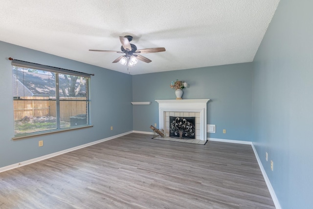 10030 Storm Meadow Dr, Houston, TX 77064 - unfurnished living room featuring a textured ceiling, ceiling fan, wood finished floors, a fireplace, and baseboards
