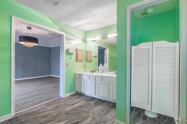 10030 Storm Meadow Dr, Houston, TX 77064 - full bathroom featuring a textured ceiling, a chandelier, double vanity, baseboards, and wood finished floors