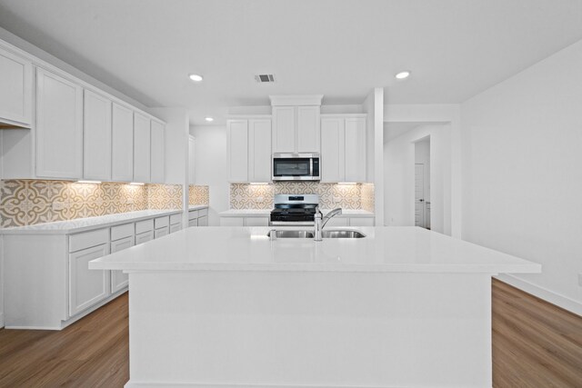 15230 Prairie Mill Dr, New Caney, TX 77357 - kitchen with stainless steel appliances, light wood-style flooring, white cabinets, tasteful backsplash, and recessed lighting