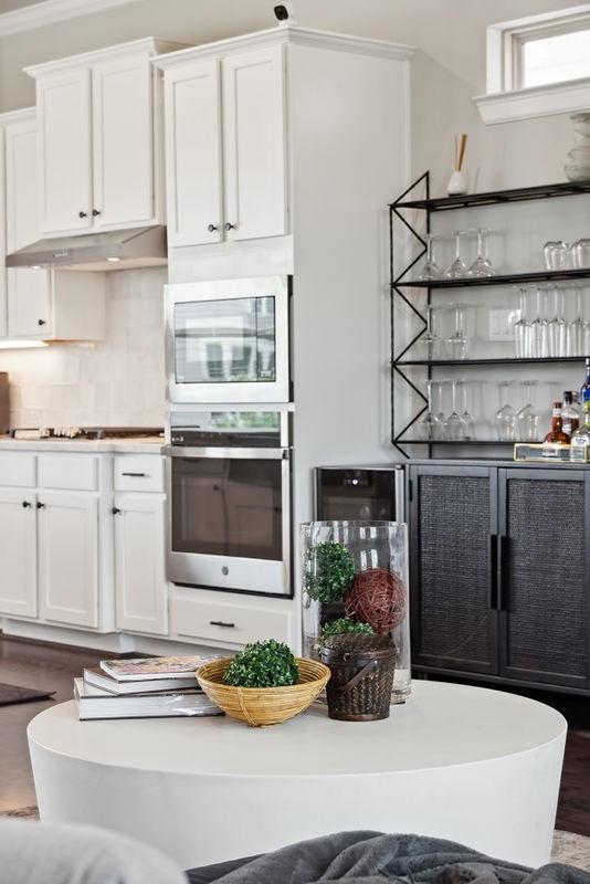 10603 Centre Green Way, Houston, TX 77043 - kitchen featuring stainless steel appliances, under cabinet range hood, decorative backsplash, white cabinetry, and wood finished floors