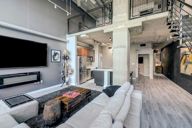2000 Bagby St Unit 5426, Houston, TX 77002 - living area featuring light wood-style floors, rail lighting, a towering ceiling, and baseboards