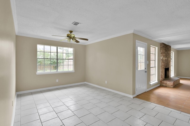 1614 Sweet Grass Trl, Houston, TX 77090 - empty room featuring a textured ceiling, ceiling fan, a brick fireplace, light tile patterned flooring, and crown molding