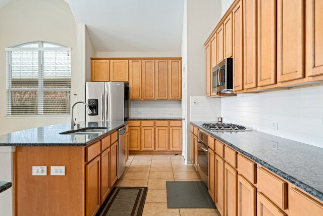 28523 Kinglet Pines Dr, Katy, TX 77494 - kitchen with a sink, appliances with stainless steel finishes, decorative backsplash, dark stone countertops, and a center island with sink