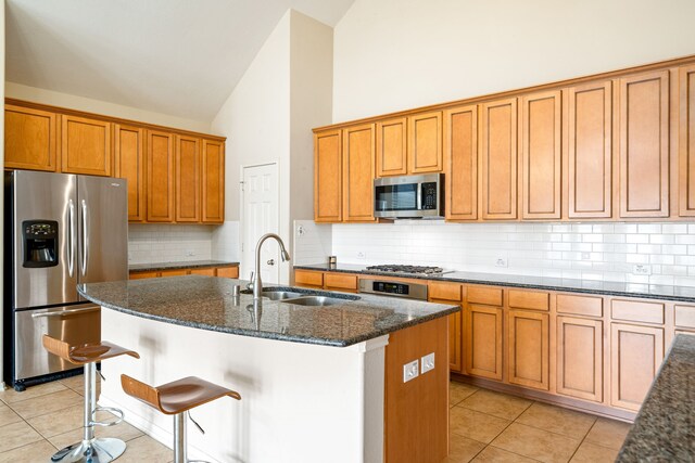 28523 Kinglet Pines Dr, Katy, TX 77494 - kitchen featuring appliances with stainless steel finishes, a sink, dark stone countertops, high vaulted ceiling, and light tile patterned flooring