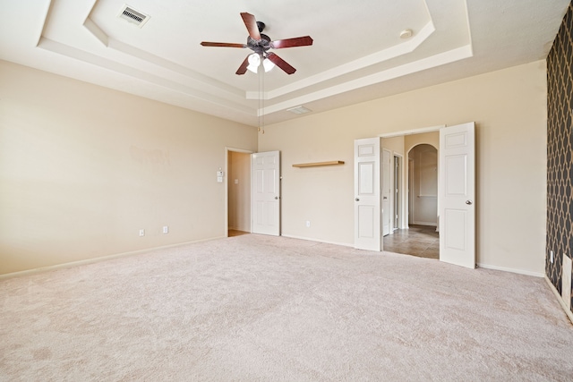 28523 Kinglet Pines Dr, Katy, TX 77494 - unfurnished bedroom featuring a tray ceiling, arched walkways, carpet floors, baseboards, and ceiling fan