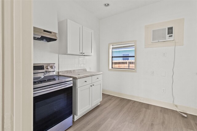 1522 Seawall Blvd, Galveston, TX 77550 - kitchen featuring stainless steel range with electric stovetop, exhaust hood, light wood-style floors, white cabinetry, and light countertops