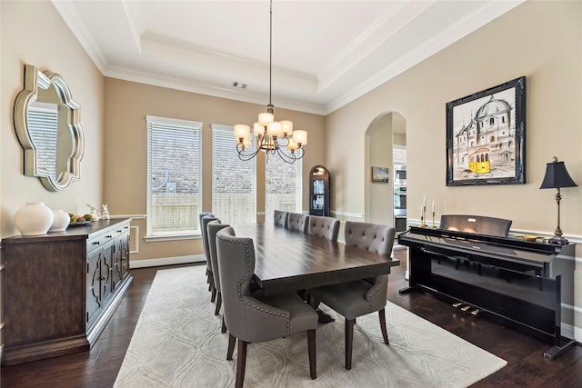 27710 Bering Crossing Dr, Katy, TX 77494 - dining space featuring arched walkways, a chandelier, dark wood-style flooring, a raised ceiling, and crown molding