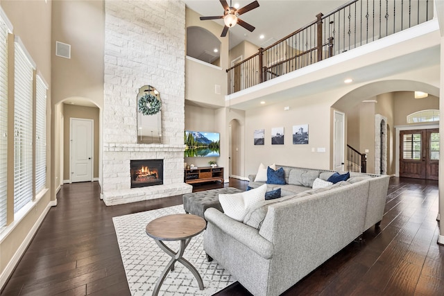 27710 Bering Crossing Dr, Katy, TX 77494 - living room featuring a towering ceiling, a ceiling fan, dark wood-style flooring, a stone fireplace, and stairway