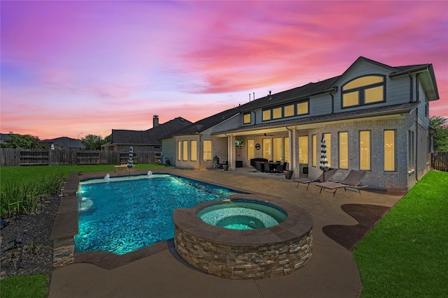 27710 Bering Crossing Dr, Katy, TX 77494 - back of property at dusk featuring a patio, a fenced backyard, brick siding, and a pool with connected hot tub