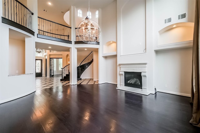 3322 Mallard Run Ct, Katy, TX 77494 - unfurnished living room featuring a chandelier, a towering ceiling, wood finished floors, stairway, and a glass covered fireplace