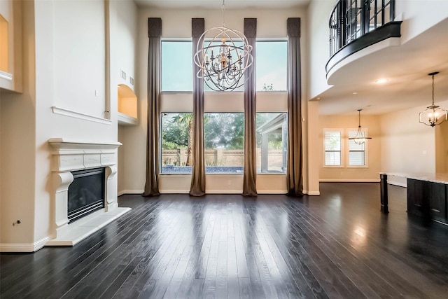 3322 Mallard Run Ct, Katy, TX 77494 - unfurnished living room with a chandelier, a glass covered fireplace, dark wood-style flooring, baseboards, and a towering ceiling