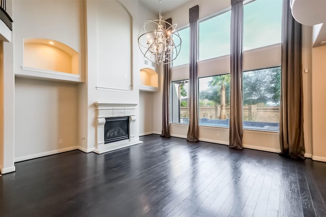 3322 Mallard Run Ct, Katy, TX 77494 - unfurnished living room featuring a glass covered fireplace, dark wood-style floors, a chandelier, a towering ceiling, and baseboards