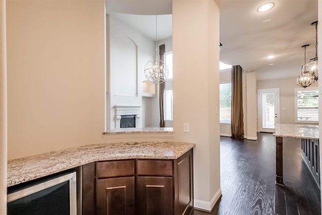 3322 Mallard Run Ct, Katy, TX 77494 - kitchen with a chandelier, a fireplace, wine cooler, dark wood-type flooring, and light stone countertops