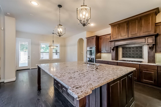 3322 Mallard Run Ct, Katy, TX 77494 - kitchen featuring appliances with stainless steel finishes, a chandelier, arched walkways, light stone counters, and recessed lighting