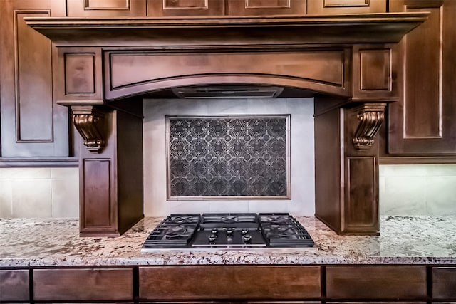 3322 Mallard Run Ct, Katy, TX 77494 - kitchen with stainless steel gas cooktop, dark brown cabinetry, light stone countertops, decorative backsplash, and arched walkways