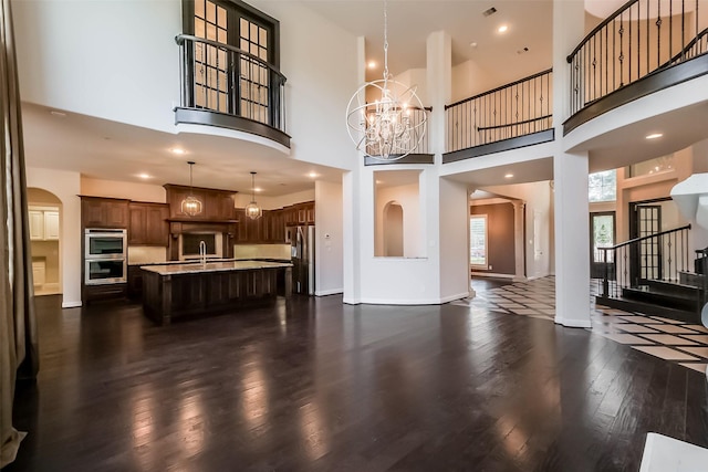 3322 Mallard Run Ct, Katy, TX 77494 - unfurnished living room with a towering ceiling, dark wood-style flooring, a sink, a chandelier, and baseboards