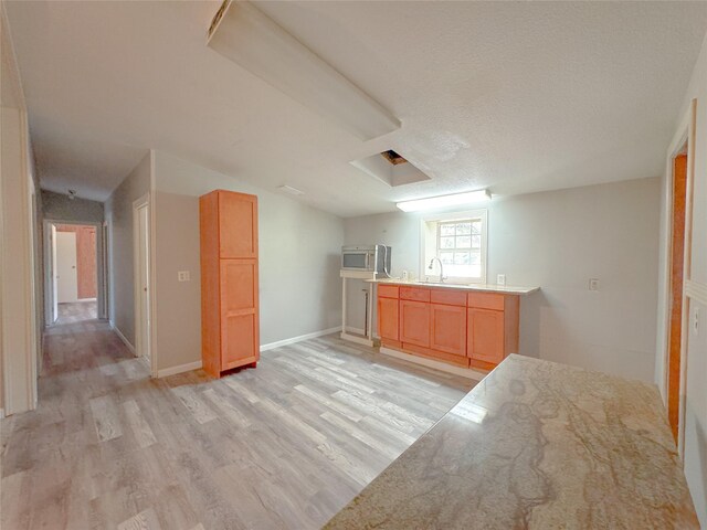 403 Fern Ln, Wharton, TX 77488 - kitchen with light wood-style floors, a sink, stainless steel microwave, and light countertops