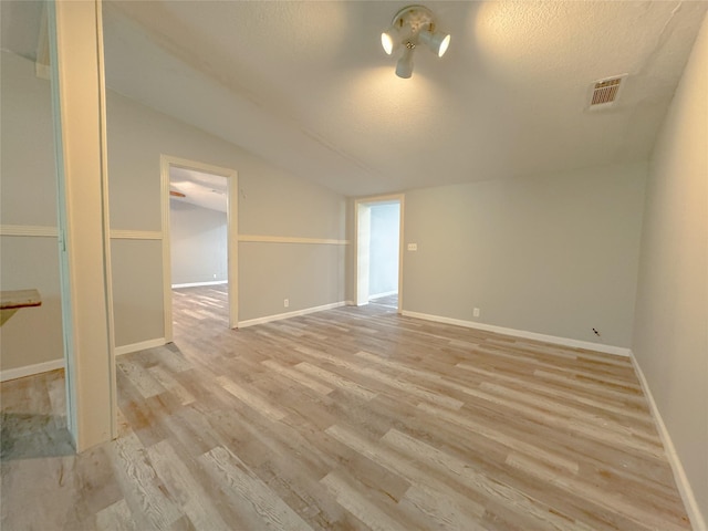 403 Fern Ln, Wharton, TX 77488 - spare room featuring lofted ceiling, light wood-style floors, baseboards, and a textured ceiling