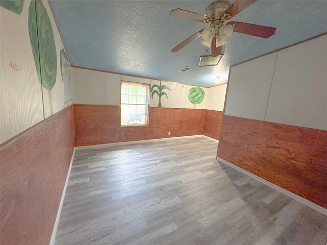 403 Fern Ln, Wharton, TX 77488 - spare room with wood finished floors, ceiling fan, a textured ceiling, wood walls, and a wainscoted wall