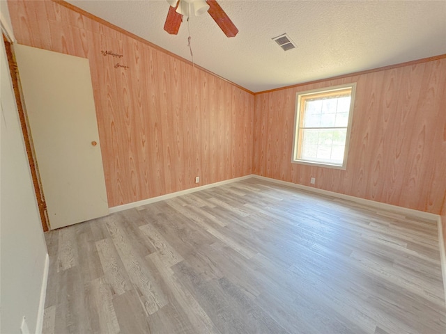 403 Fern Ln, Wharton, TX 77488 - spare room featuring light wood-style flooring, ceiling fan, a textured ceiling, and wooden walls