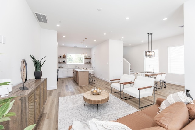 1613 Erin St, Houston, TX 77009 - living area with a chandelier, stairway, recessed lighting, light wood-style floors, and baseboards