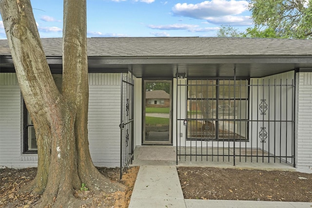 2635 Dragonwick Dr, Houston, TX 77045 - view of exterior entry featuring a shingled roof and brick siding