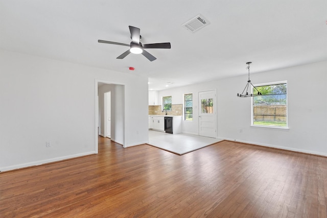 2635 Dragonwick Dr, Houston, TX 77045 - unfurnished living room featuring a chandelier, wood finished floors, baseboards, ceiling fan, and a sink