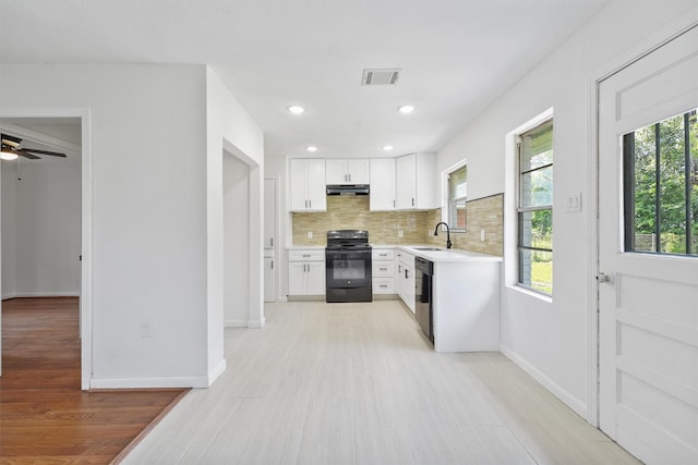 2635 Dragonwick Dr, Houston, TX 77045 - kitchen with black electric range, a sink, light countertops, tasteful backsplash, and white cabinets