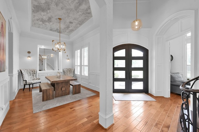 28310 Whispering Maple Way, Spring, TX 77386 - entryway featuring a tray ceiling, a decorative wall, light wood finished floors, a chandelier, and arched walkways