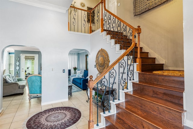 15110 Farndale Dr, Houston, TX 77062 - stairway featuring arched walkways, crown molding, tile patterned flooring, baseboards, and a high ceiling