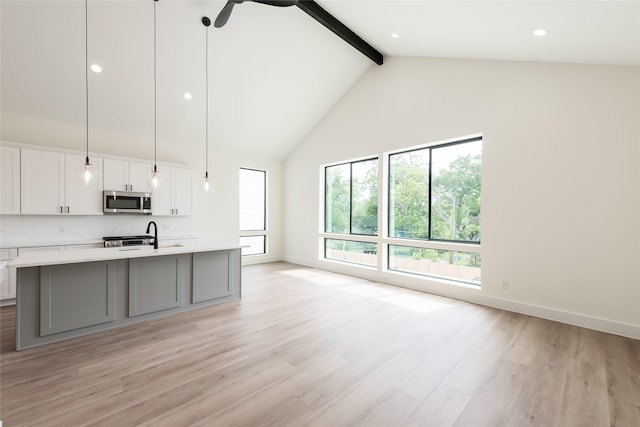6137 Pacific Forest Dr, Houston, TX 77346 - kitchen with stainless steel microwave, beamed ceiling, light countertops, high vaulted ceiling, and an island with sink