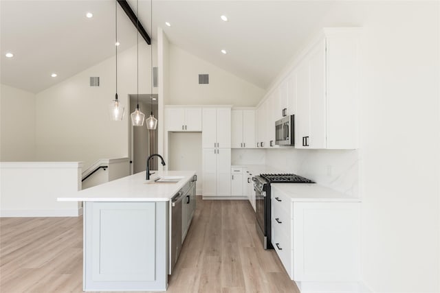 6137 Pacific Forest Dr, Houston, TX 77346 - kitchen with stainless steel appliances, light wood finished floors, a sink, white cabinetry, and a center island with sink