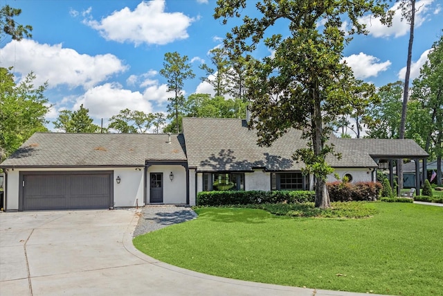 view of front facade featuring a garage, a front yard, concrete driveway, and stucco siding