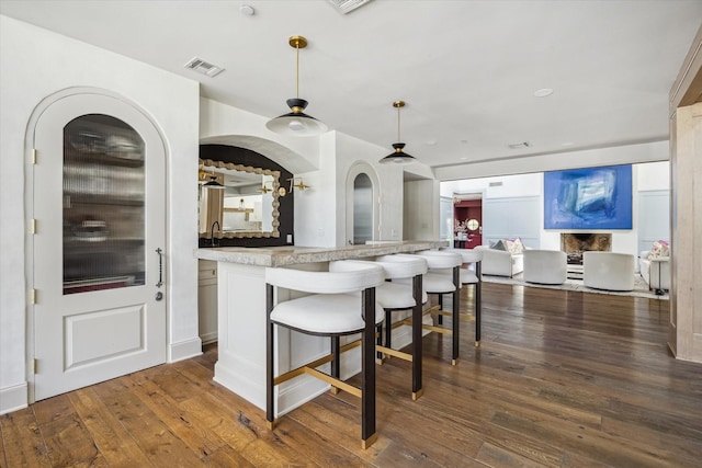 kitchen featuring open floor plan, dark wood finished floors, pendant lighting, and a breakfast bar area