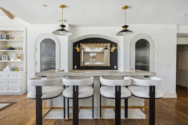 indoor bar featuring light wood-style floors and hanging light fixtures