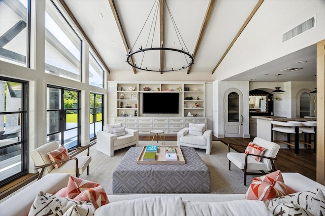 living area with high vaulted ceiling, a chandelier, beam ceiling, wood finished floors, and arched walkways