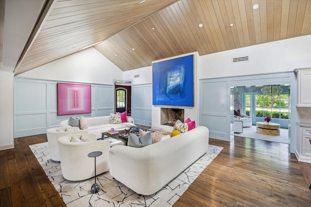 living area with a decorative wall, healthy amount of natural light, wood-type flooring, a fireplace, and wooden ceiling