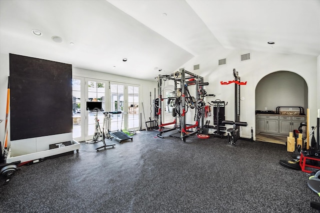 exercise room featuring lofted ceiling, arched walkways, recessed lighting, and french doors
