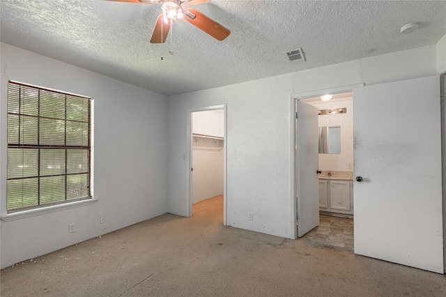 2240 Easley Cir, Huntsville, TX 77320 - unfurnished bedroom with a textured ceiling, a walk in closet, connected bathroom, a closet, and a ceiling fan