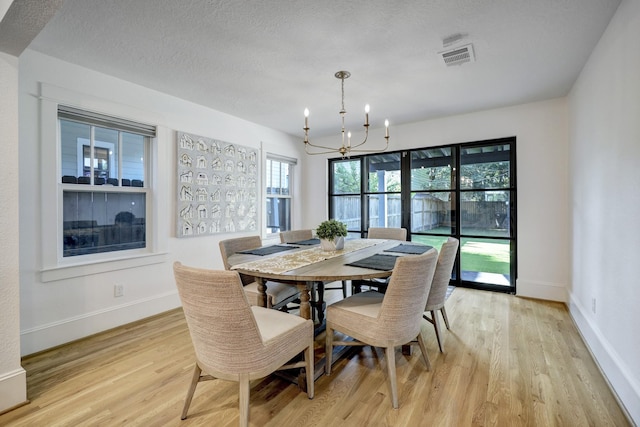412 Merrill St, Houston, TX 77009 - dining space featuring a chandelier, light wood-style flooring, baseboards, and a textured ceiling